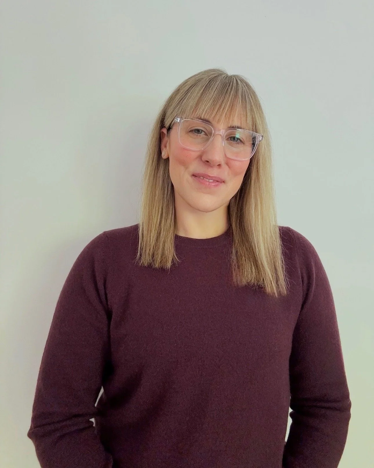 female with blond hair, glasses, smiling