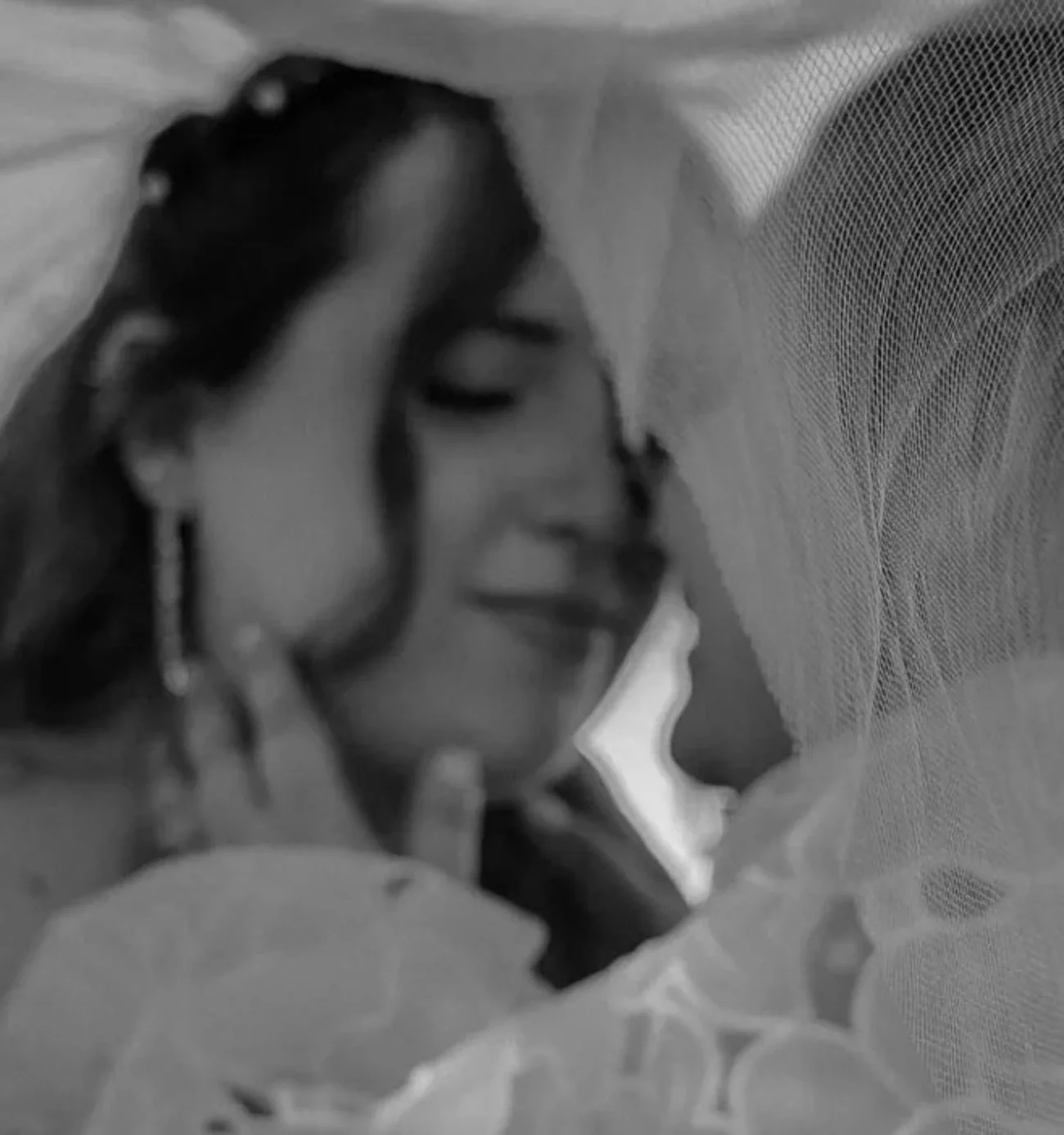 Black and white close-up photo of a two women smiling with their heads close together, embracing each other.