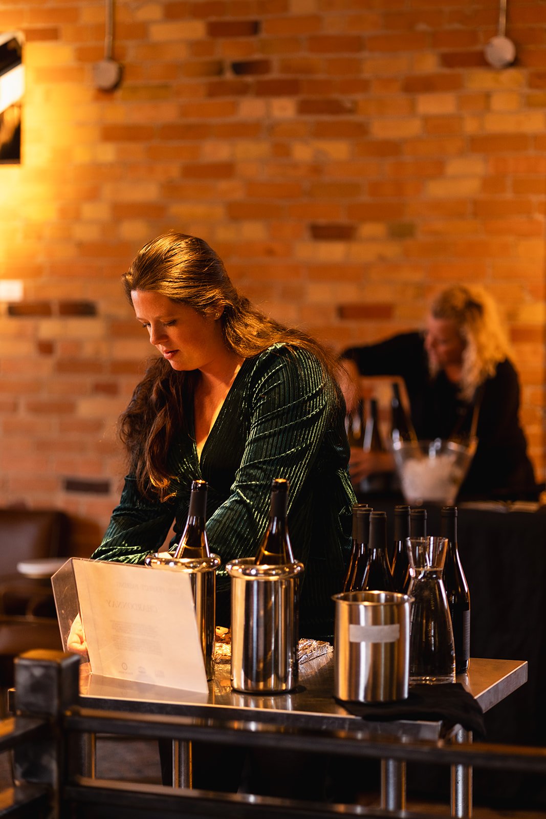 A women, setting up an intimate event she planned. An expert in food, beverage, hospitality and hosting events. Women in green dress, hostess, service, wine tasting, cheese pairing