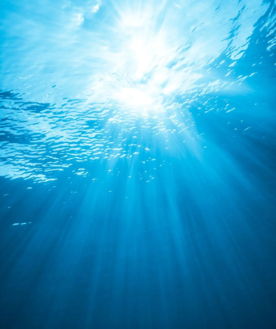 Sun rays penetrating clear blue ocean water from above.
