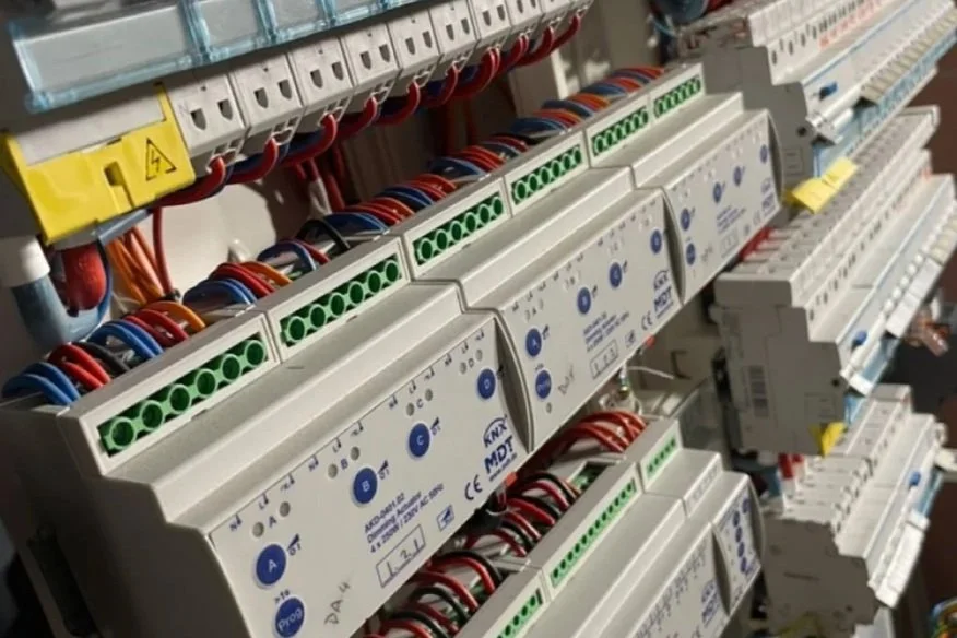 Electrical control panel with rows of circuit breakers and terminal strips connected by multicolored wires