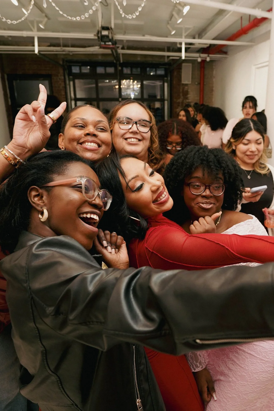Group of diverse women taking a selfie and smiling at an indoor gathering.