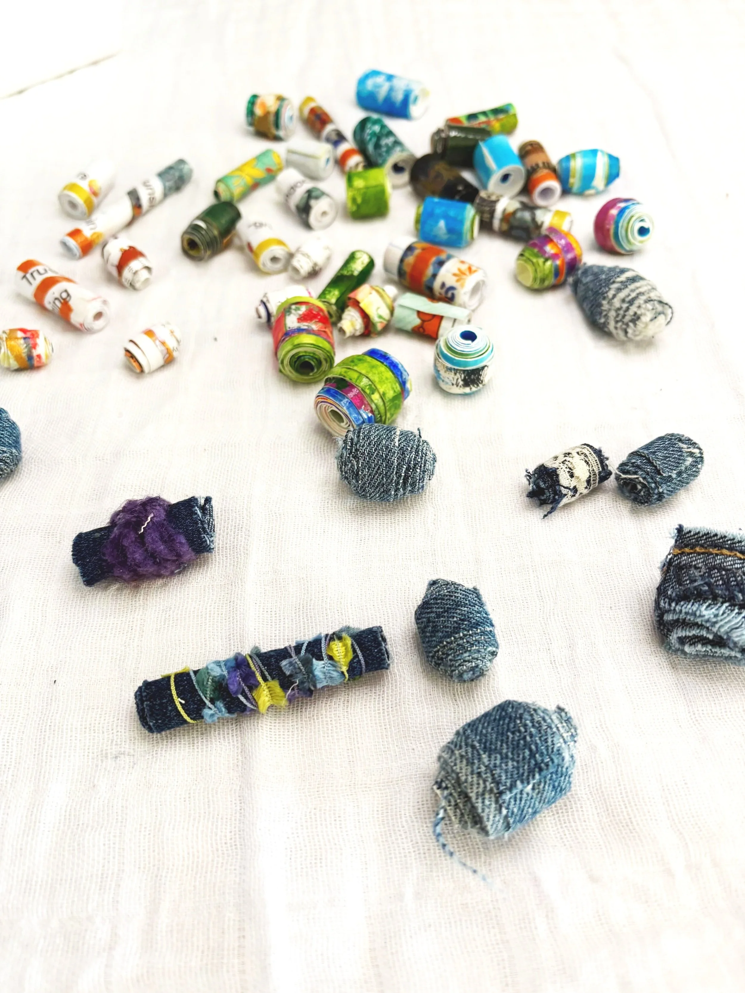 Colorful rolls of fabric or paper and small fabric scraps scattered on a white surface.