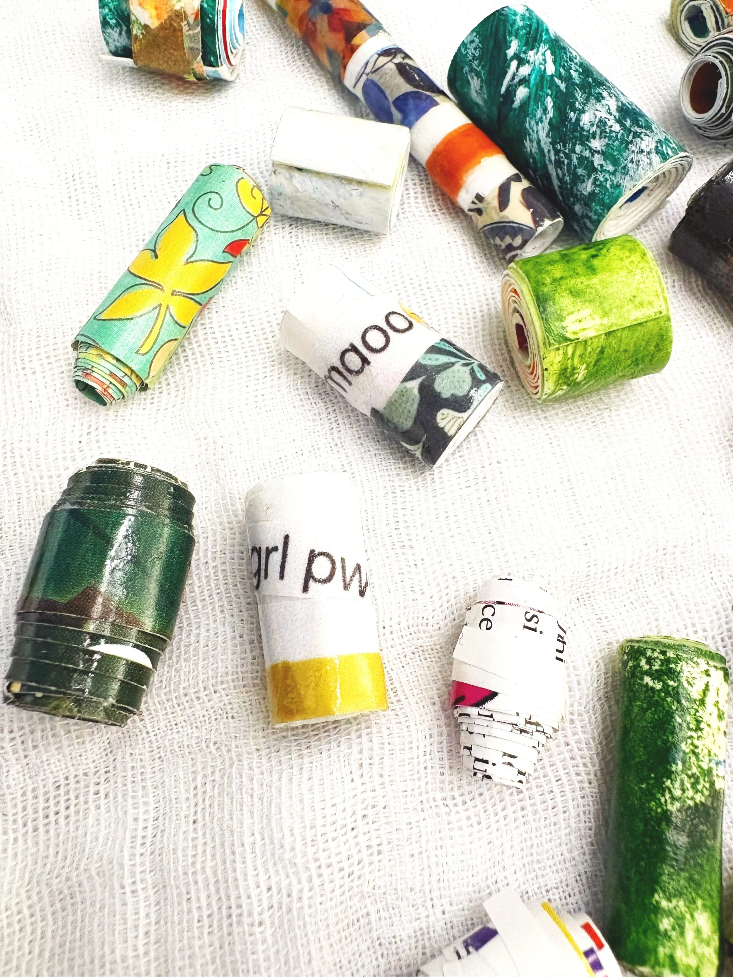 Multiple used and empty colorful toilet paper rolls scattered on a white textured surface.