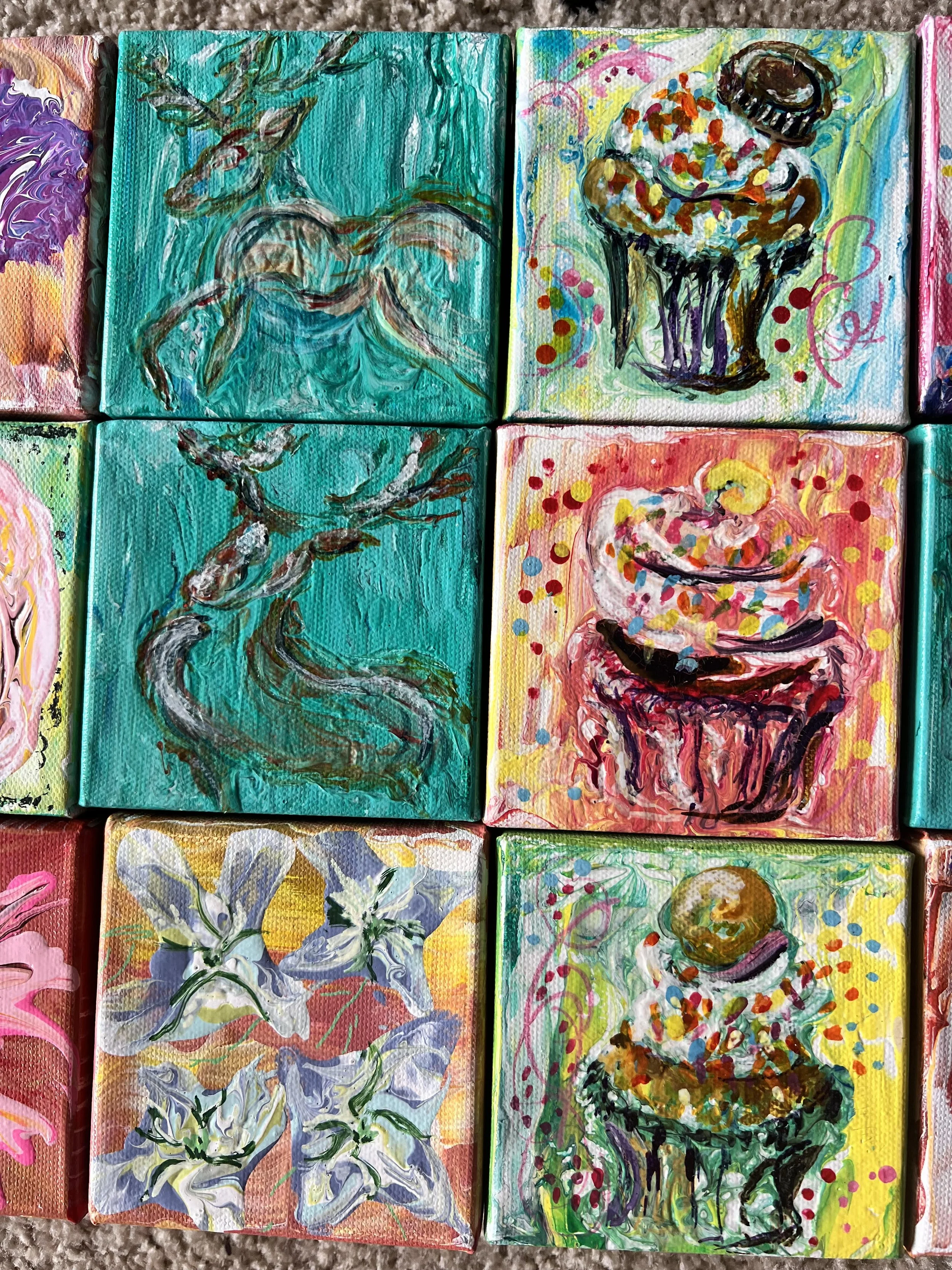 Four small, colorful, abstract paintings on paper or canvas, each featuring vibrant brushstrokes and diverse patterns including flowers, a cupcake, a deer, and a chocolate chip cookie.