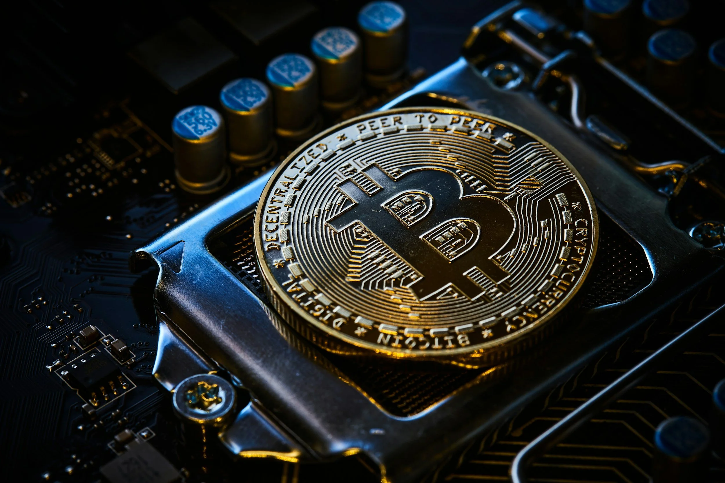 Close-up of a Bitcoin coin placed on a computer circuit board.