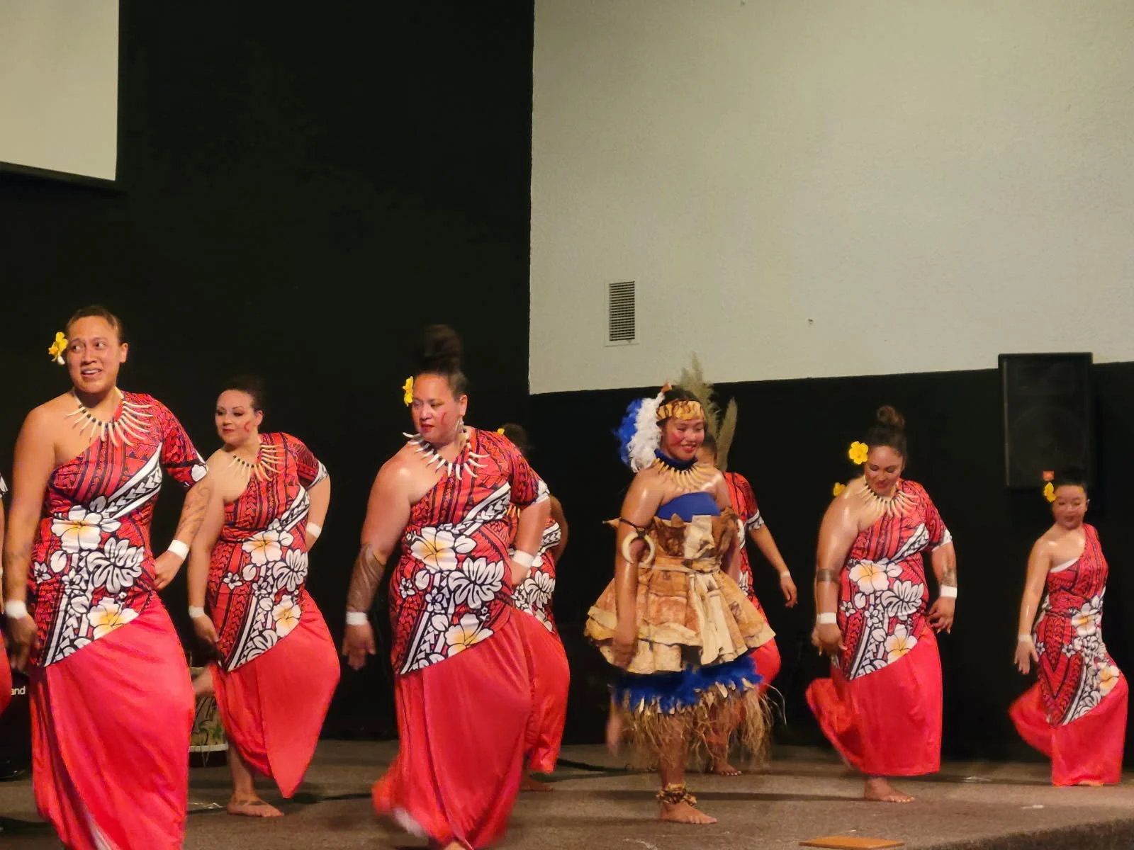 Group of dancers in traditional Polynesian costumes performing on stage.