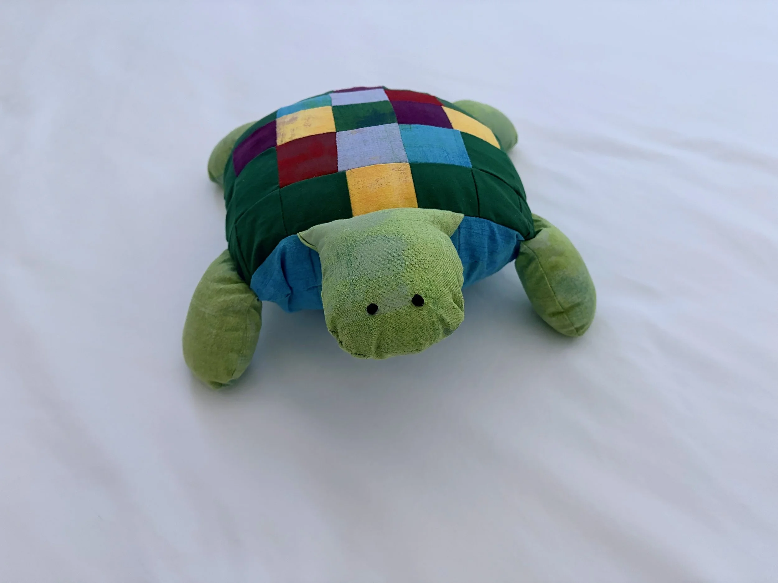 Colorful patchwork stuffed turtle toy on a plain white surface.