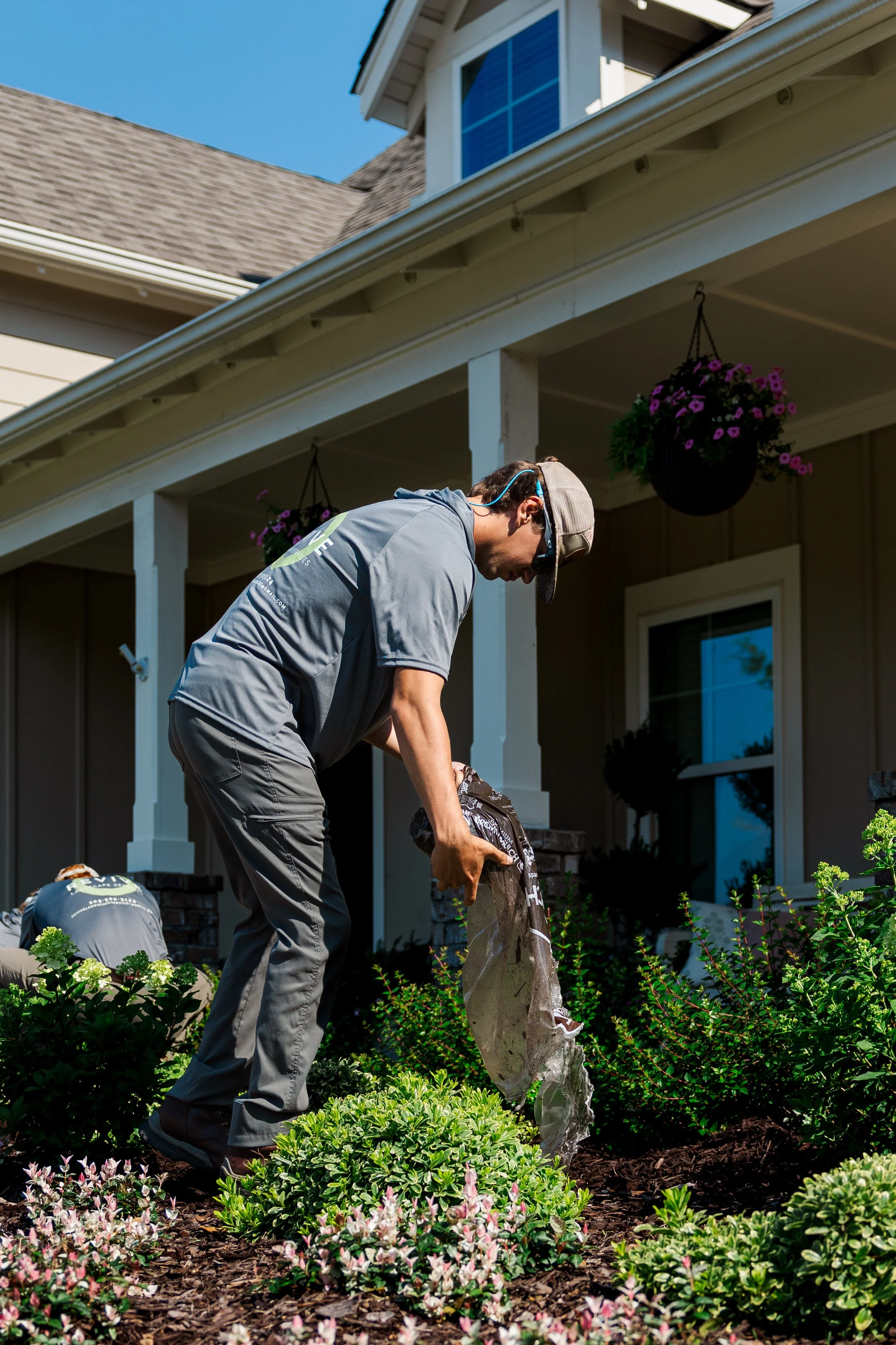 Revive Landscape Helena Alabama A man planting a tree in a garden in front of a house during daytime.