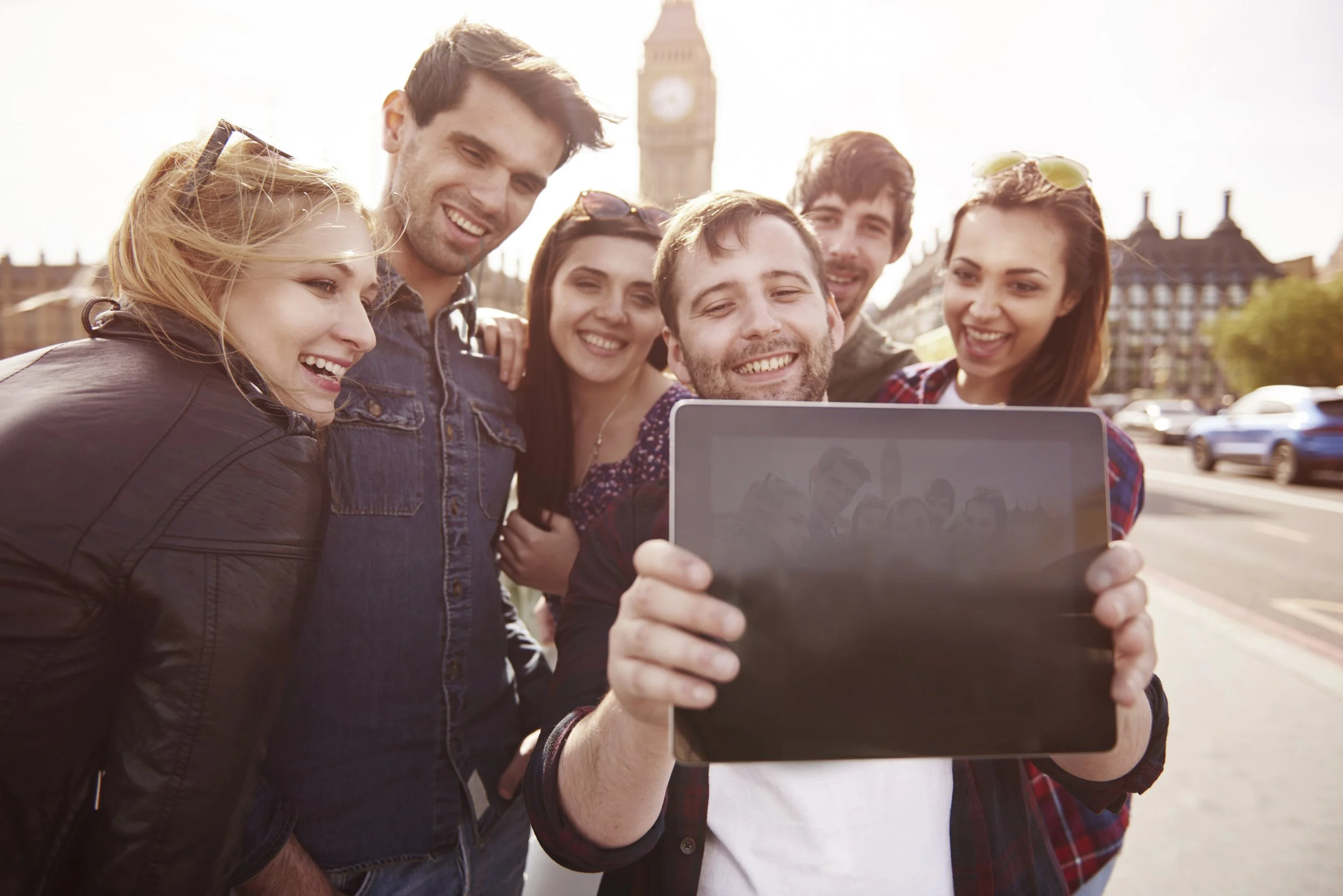 Group of six young adults taking a selfie outdoors with Big Ben in the background.
