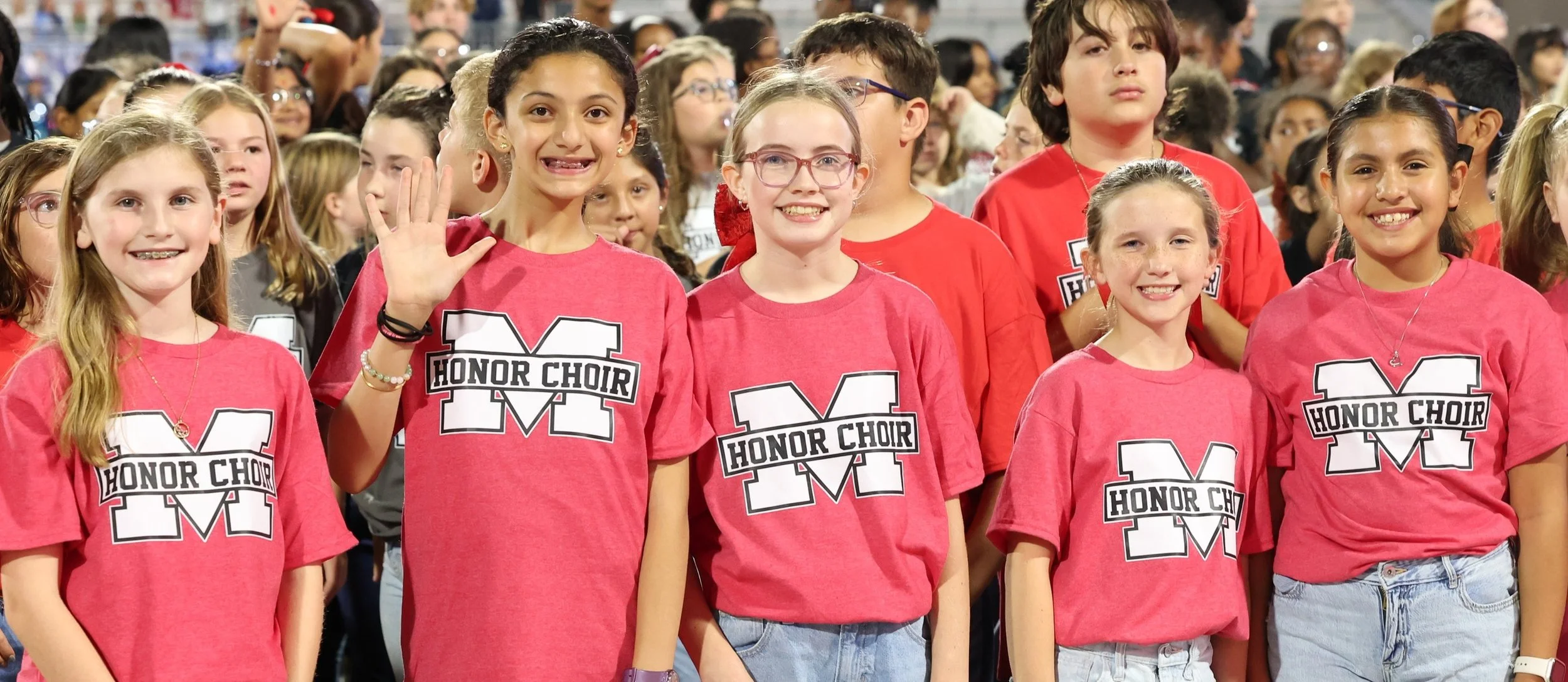 students posing at a football game from the elementary honor choir