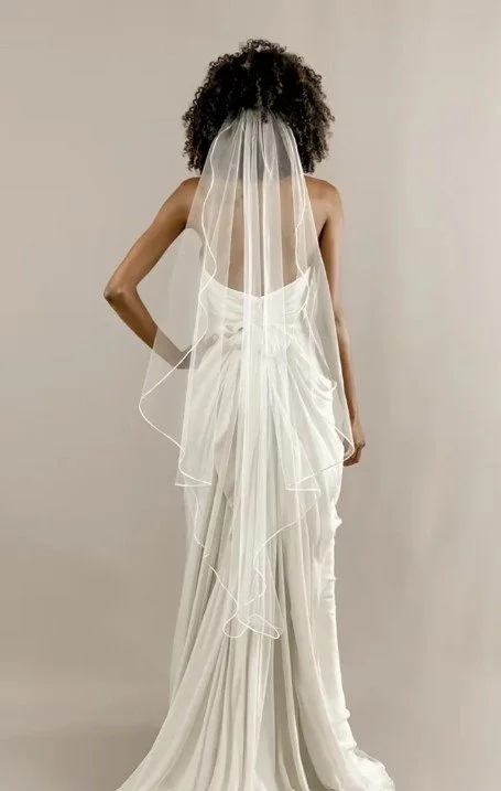 Back view of a woman in a white wedding dress with a veil.