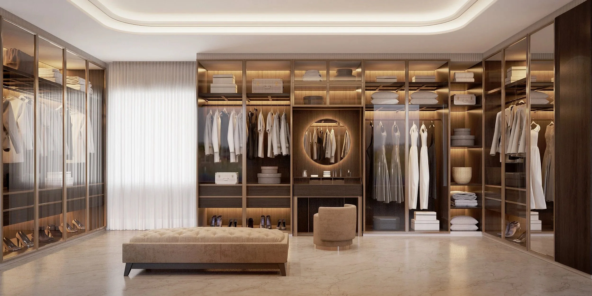 A walk-in closet with glass-front closets filled with clothing, shoes, and accessories, a plush ottoman, and a small upholstered chair.