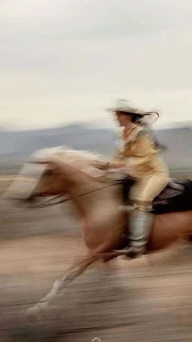 Une personne à cheval galopant sur une plage, avec un fond de ciel et d'océan.