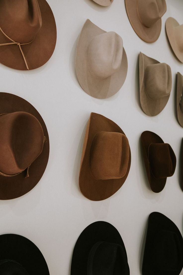 Une collection de chapeaux de différentes couleurs et styles accrochés au mur.