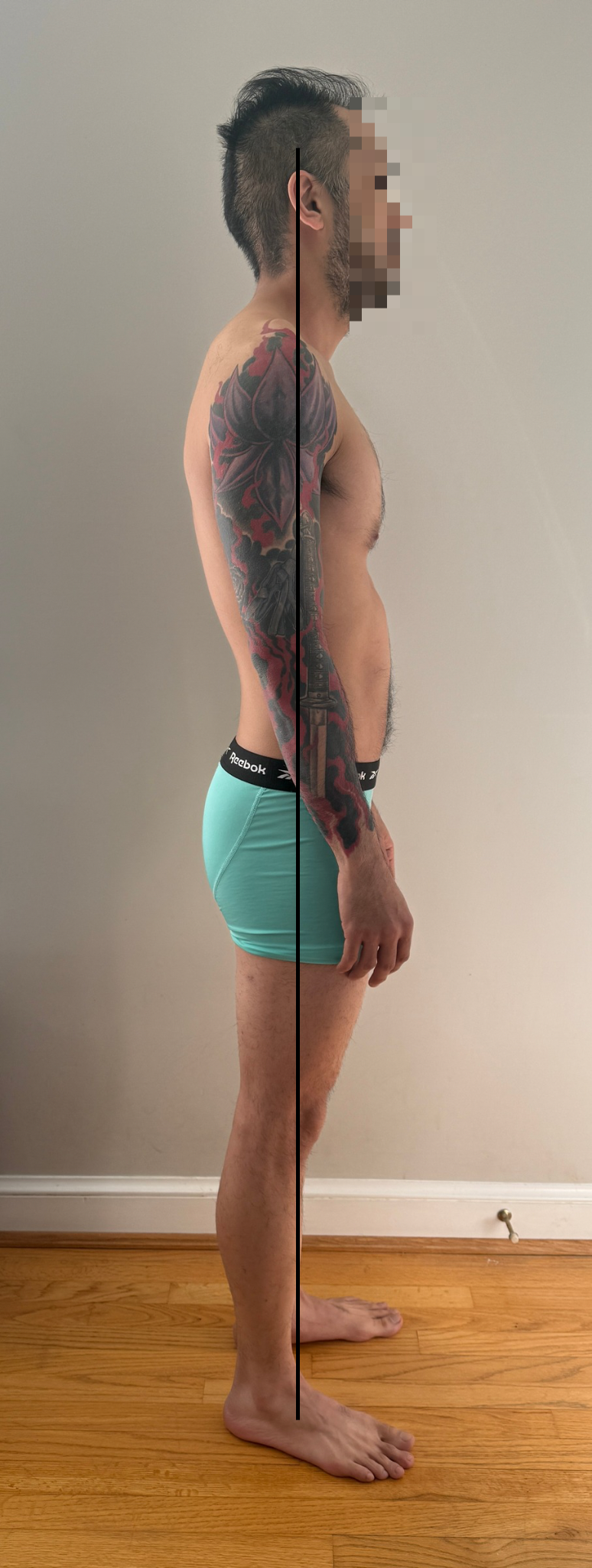 A side view of a shirtless man with blue shorts, standing against a plain wall and wooden floor, with a black line down the middle showing a comparison perspective.