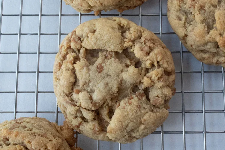 Close-up of a freshly baked oatmeal chocolate chip cookie on a cooling rack. Frozen Custard East Vancouver, BC