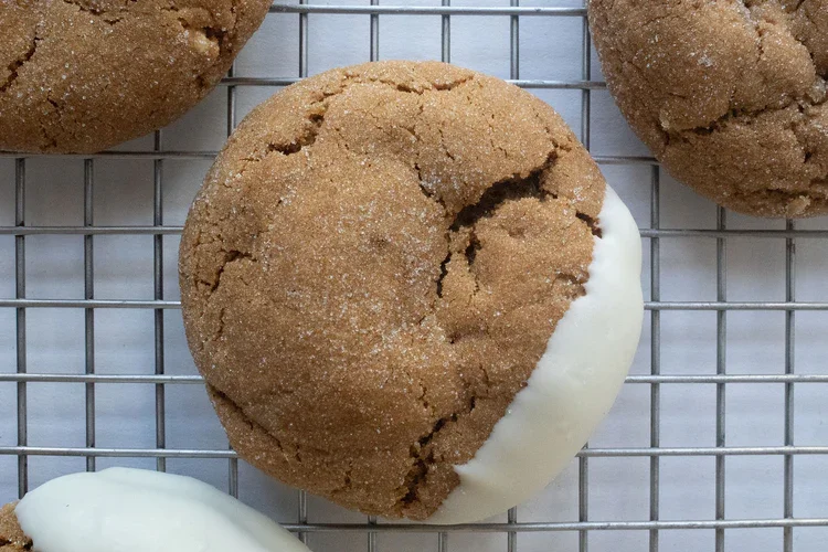 A cookie with half white icing on a wire rack, surrounded by other cookies. Frozen Custard East Vancouver, BC
