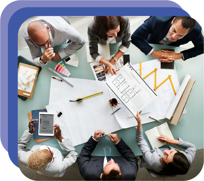 A group of six professionals gathered around a table with architectural plans, laptops, and tablets, engaged in a discussion and planning.
