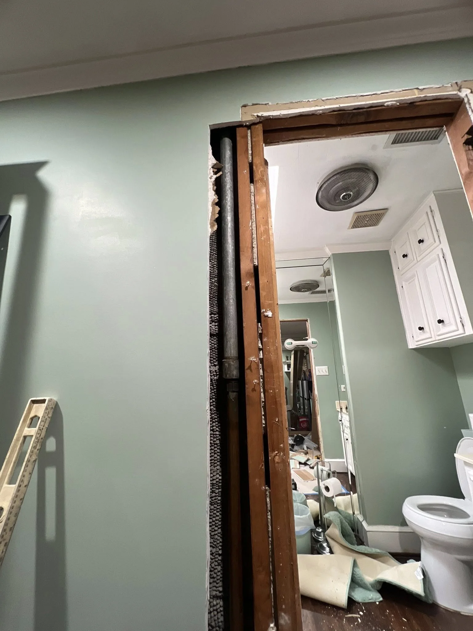 Bathroom under renovation with exposed wooden framing, construction tools, and supplies scattered around.