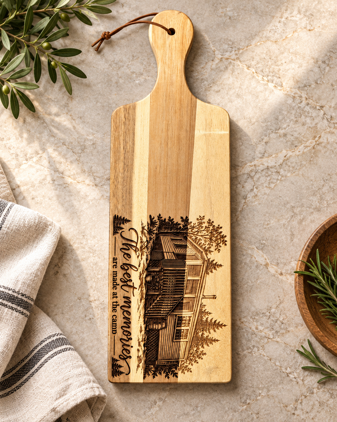 Wooden cutting board with engraved house and trees, and the words 'Hey there, my neighbor' and 'are made at the camp' on a marble countertop, accompanied by a beige and black striped napkin and green plants.