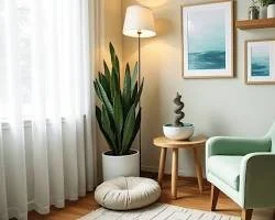 Living room corner with a large potted plant, a mint green armchair, a small wooden side table with a decorative sculpture, and framed ocean-themed artwork on the wall.