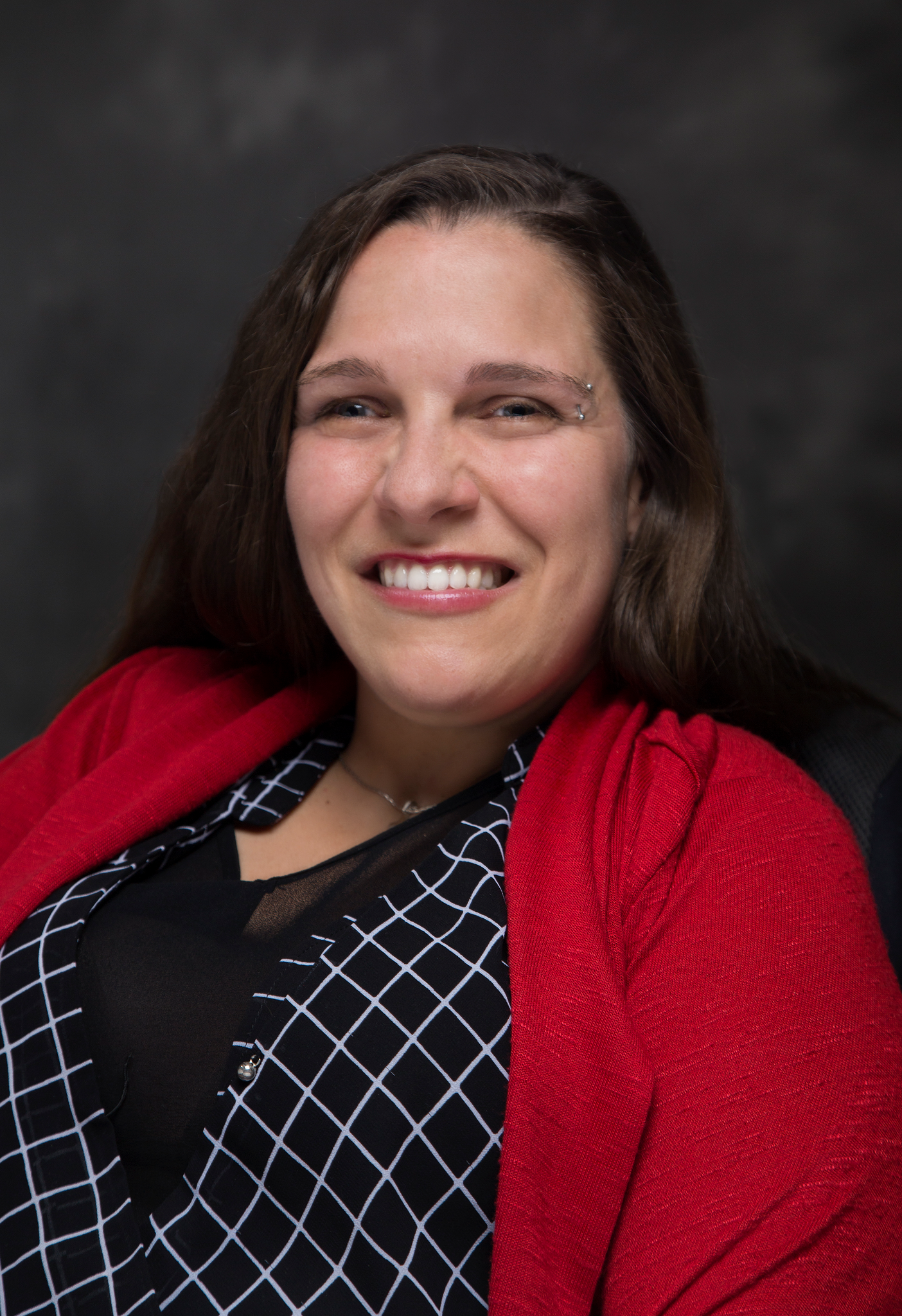 Councillor Chantal Huinink poses for a headshot, wearing a red cardigan and a black and white checkered shirt. She smiles.