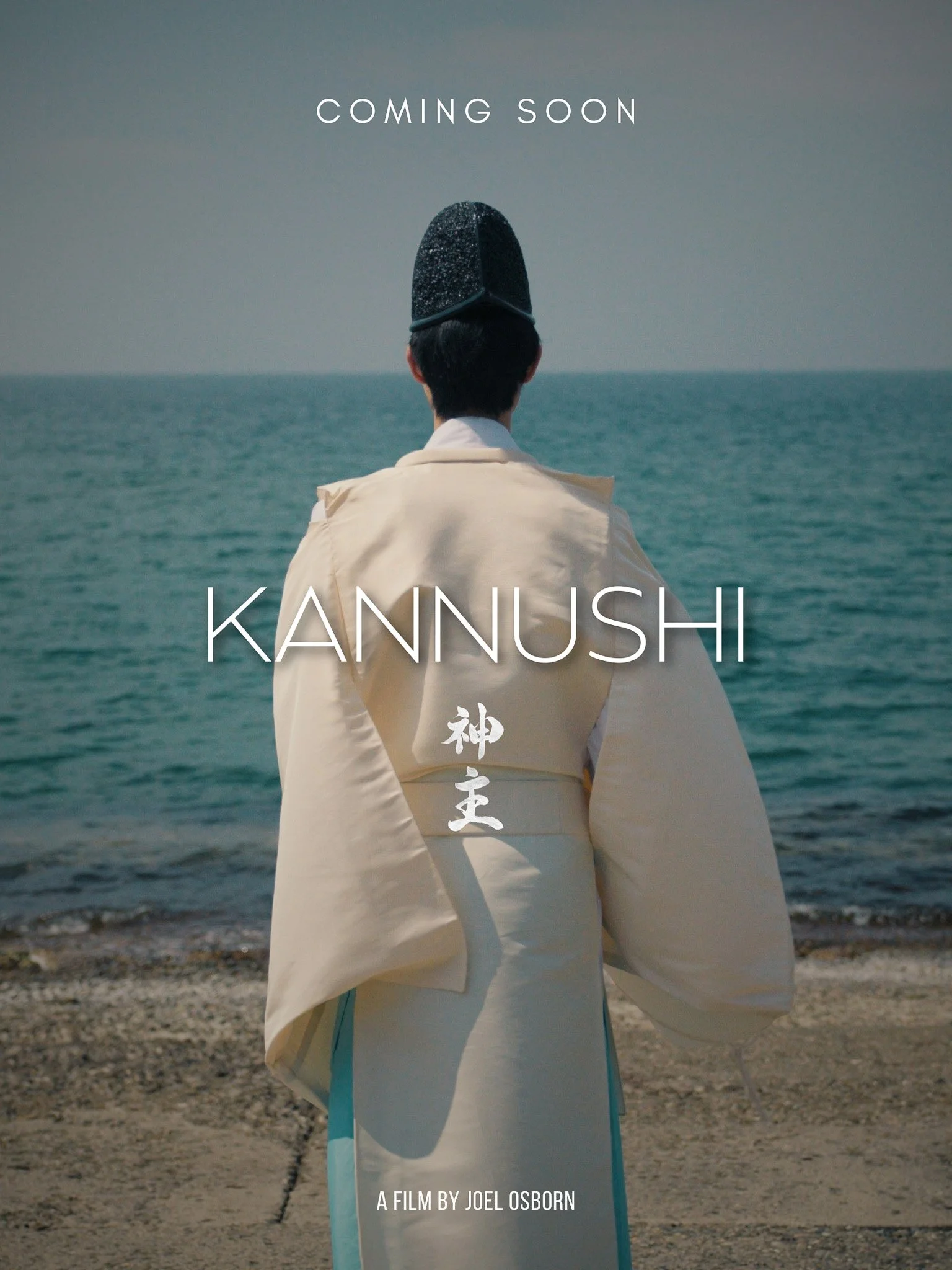 Person dressed in traditional Japanese clothing with a hat, standing on a beach facing the ocean, with the words 'Coming Soon' and 'KANNUSHI' written on the image, and a line of Japanese characters below.