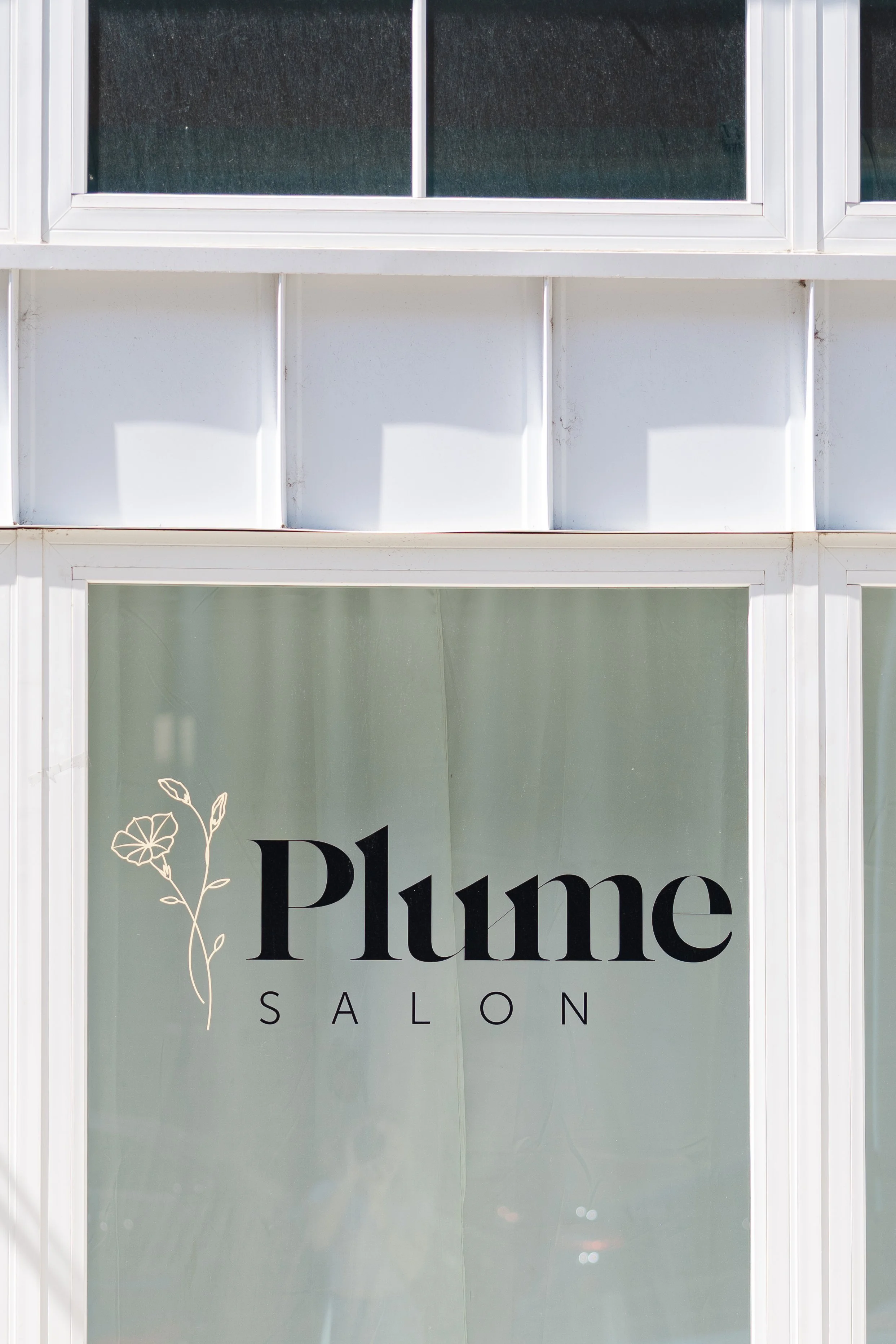 A storefront window with a sign that reads 'Plume Salon' and a flower illustration.