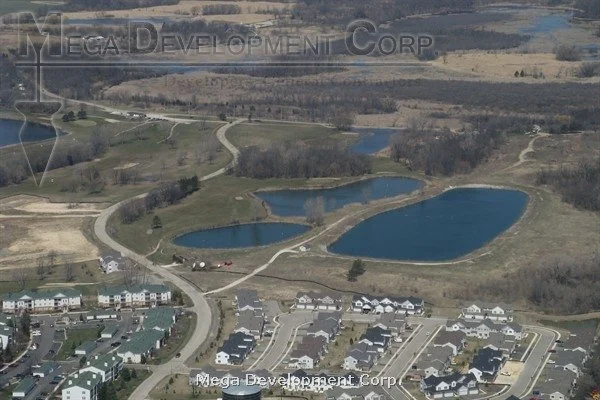 Aerial view of a residential neighborhood adjacent to a park with multiple small lakes and winding walking paths.