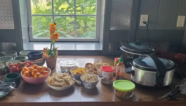 Homemade food with a variety of food items including soups, apples, oranges, bread, snacks, and condiments, from the Silent Retreats.