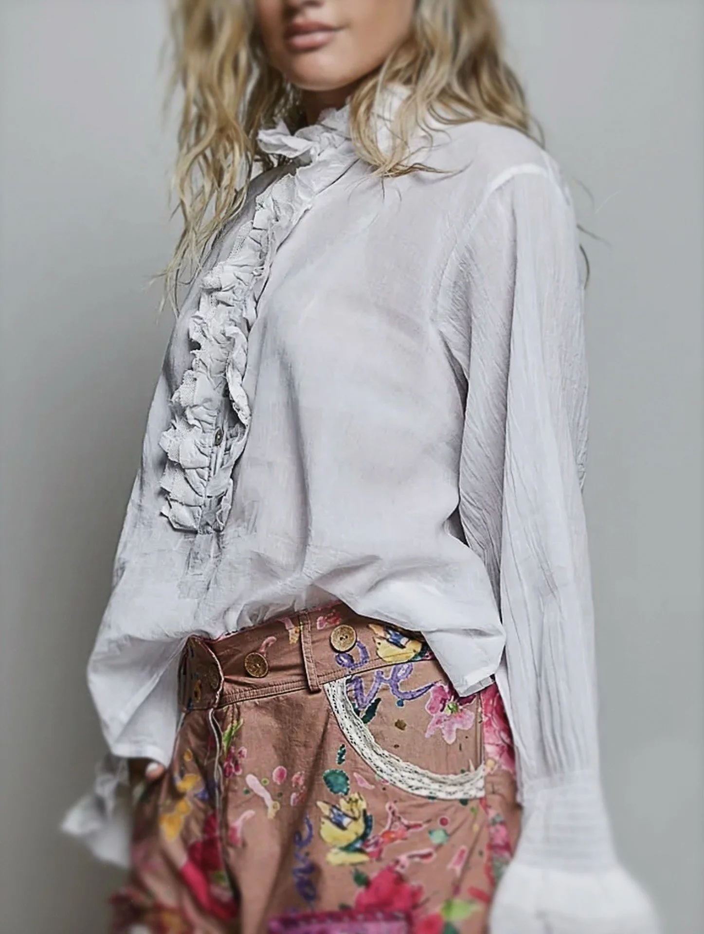 White long-sleeve ruffle blouse styled with a pink patterned skirt.