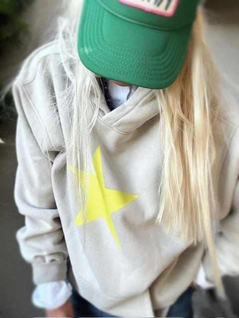Close-up of neon yellow star detail on cream women's hoodie