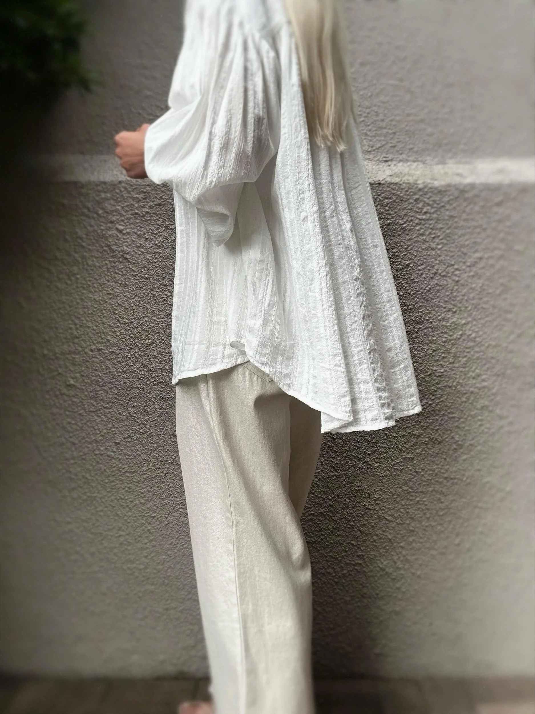 Flowing side hem of the Banditas Flegrei oversized shirt styled with cream pants