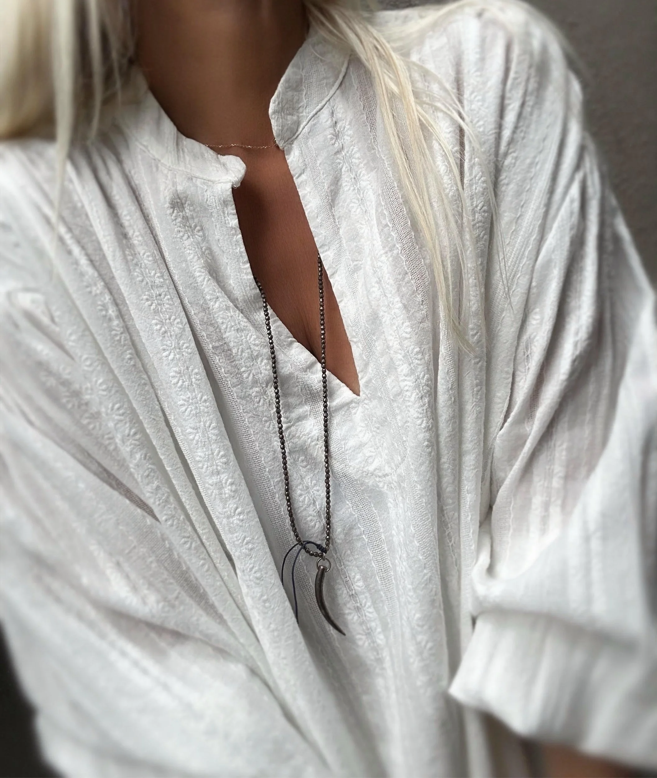 Close-up of the open neckline and metallic striped texture of the Flegrei shirt