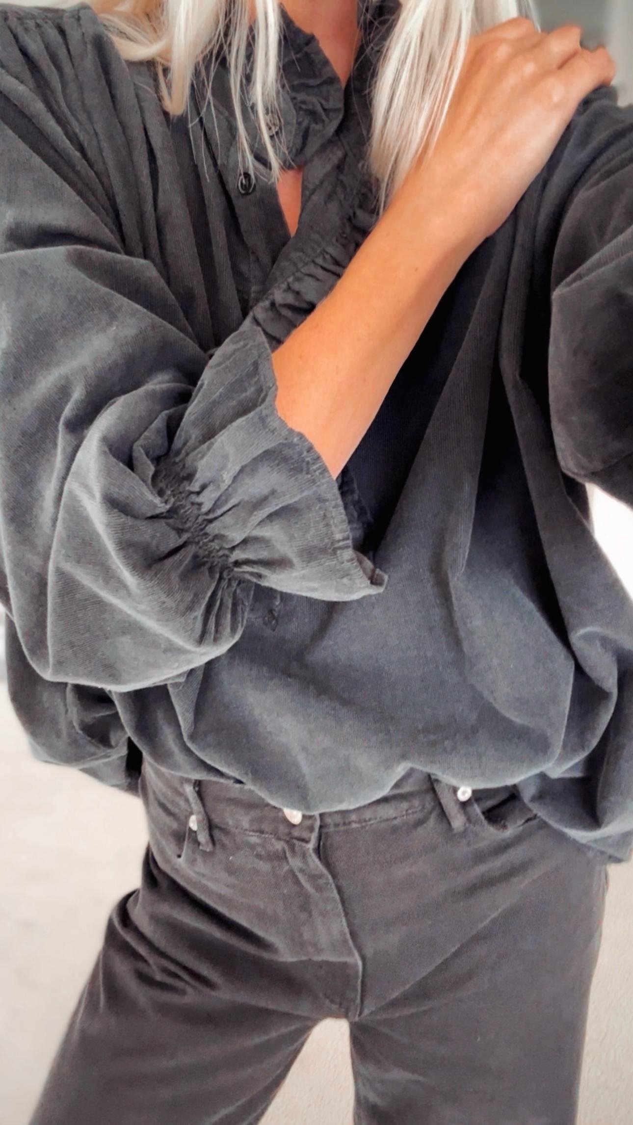 Close-up of the delicate corduroy texture and ruffle detailing on the black blouse.