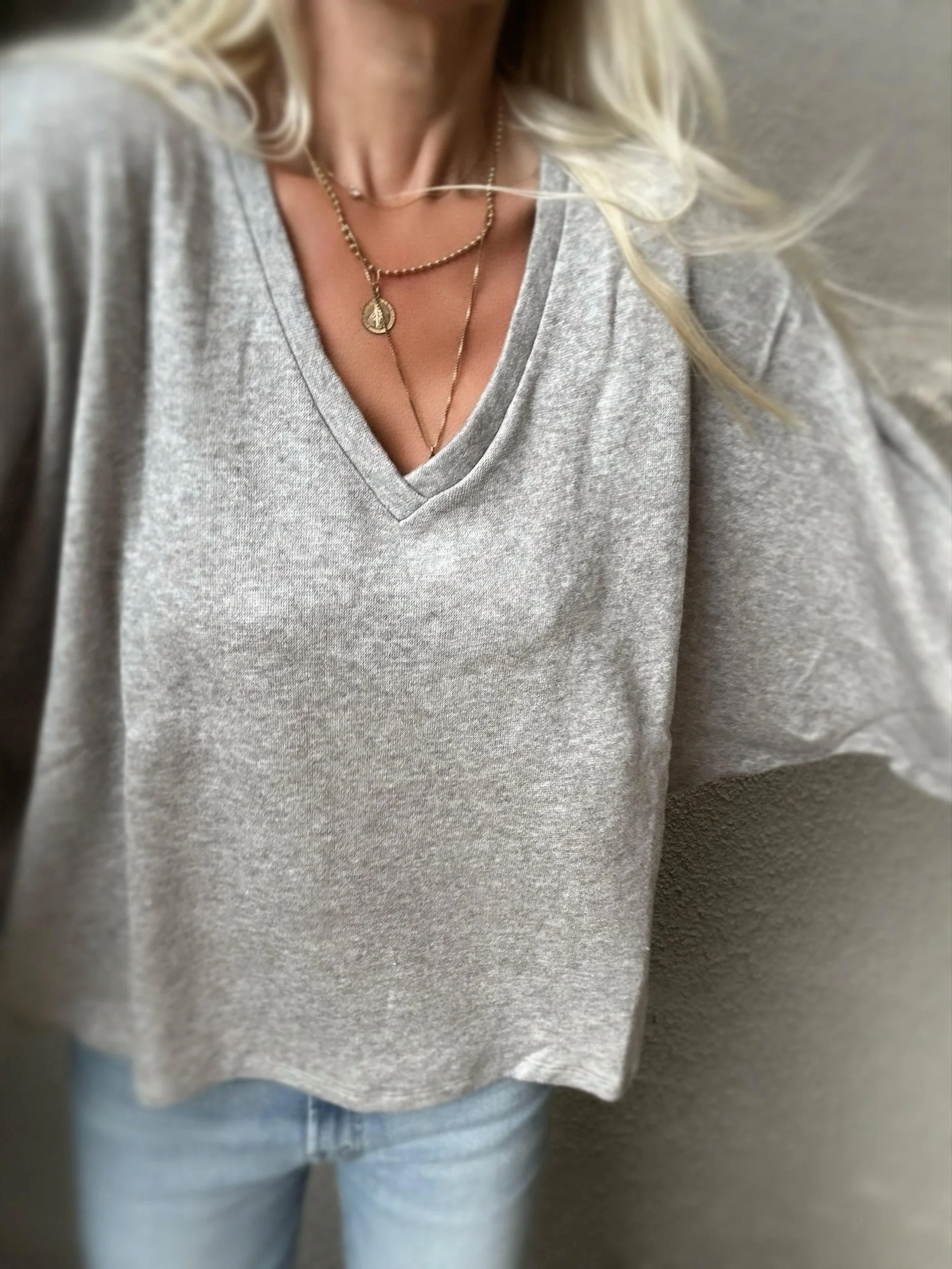 Woman wearing the grey Banditas Haiku V-Neck Sweatshirt showing its wide sleeves and relaxed hem