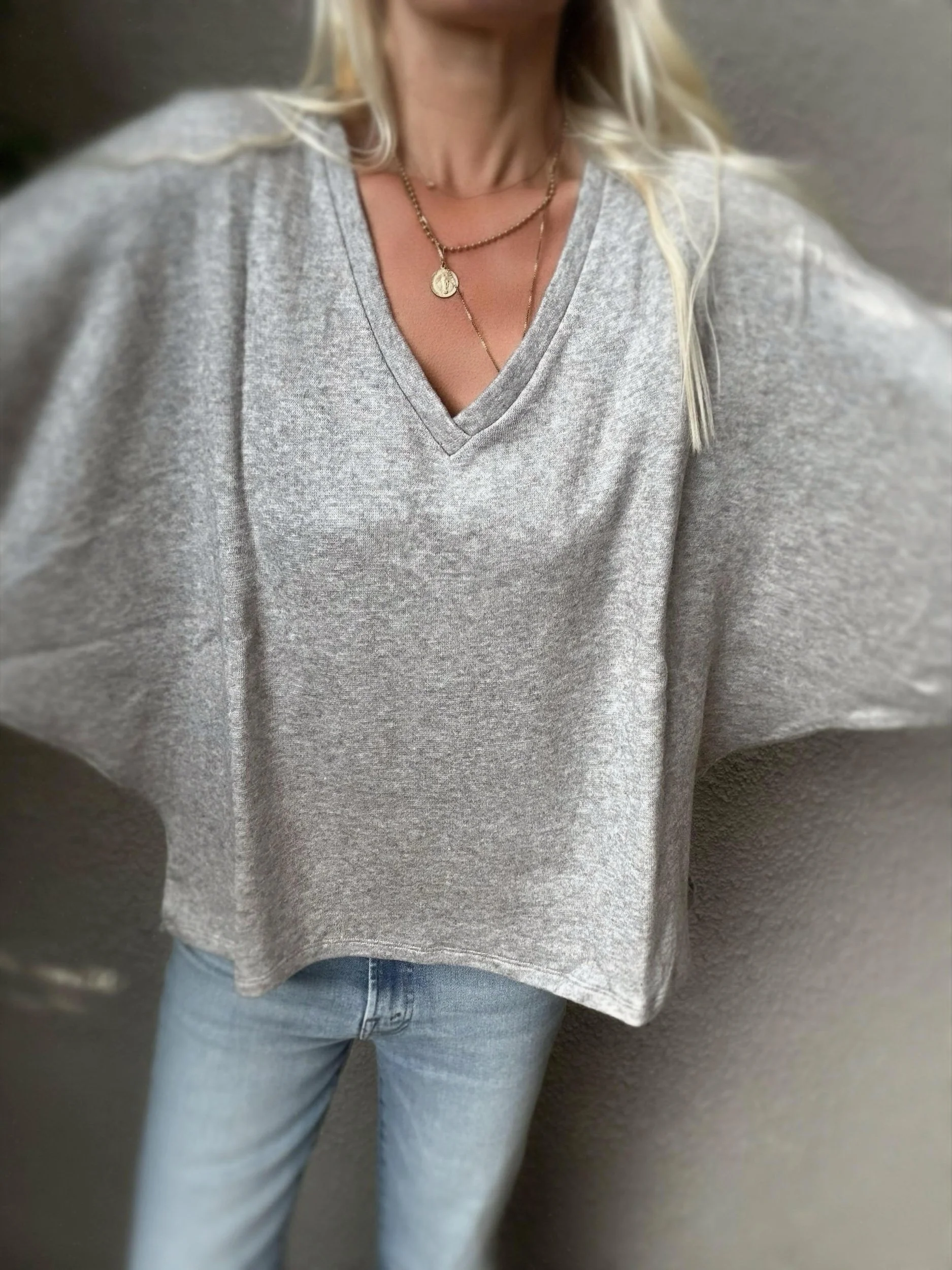 Woman wearing the grey Banditas Haiku V-Neck Sweatshirt with an oversized fit and wide sleeves