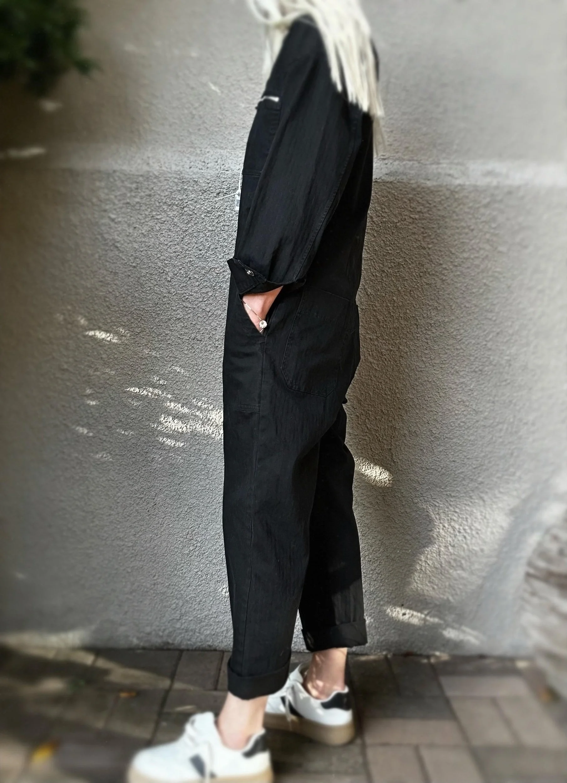 Side view of black Banditas Hana Jumpsuit showing its loose silhouette and cropped legs