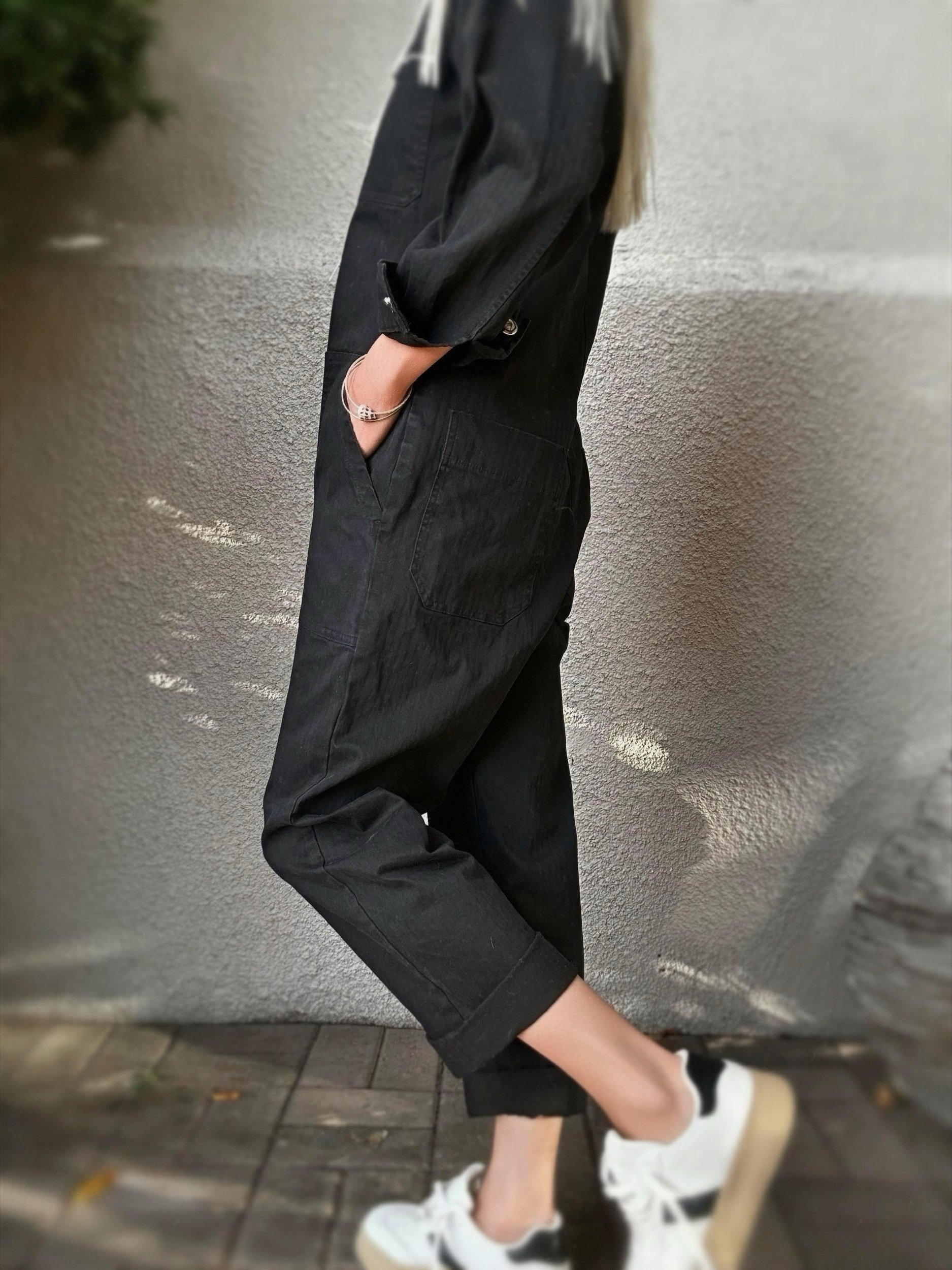 Woman wearing the black Banditas Hana Jumpsuit with hands in pockets, showing its relaxed fit