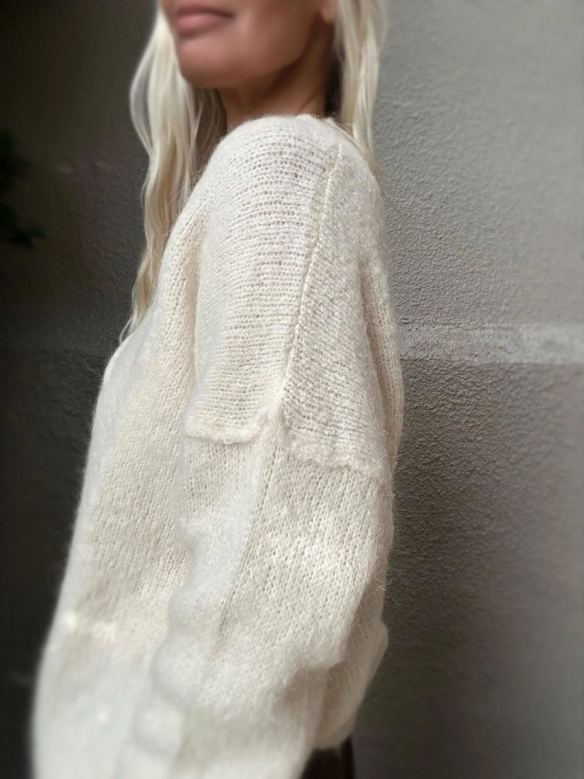 Side view of cream Banditas Kula V-Neck Sweater highlighting its oversized sleeves and relaxed silhouette