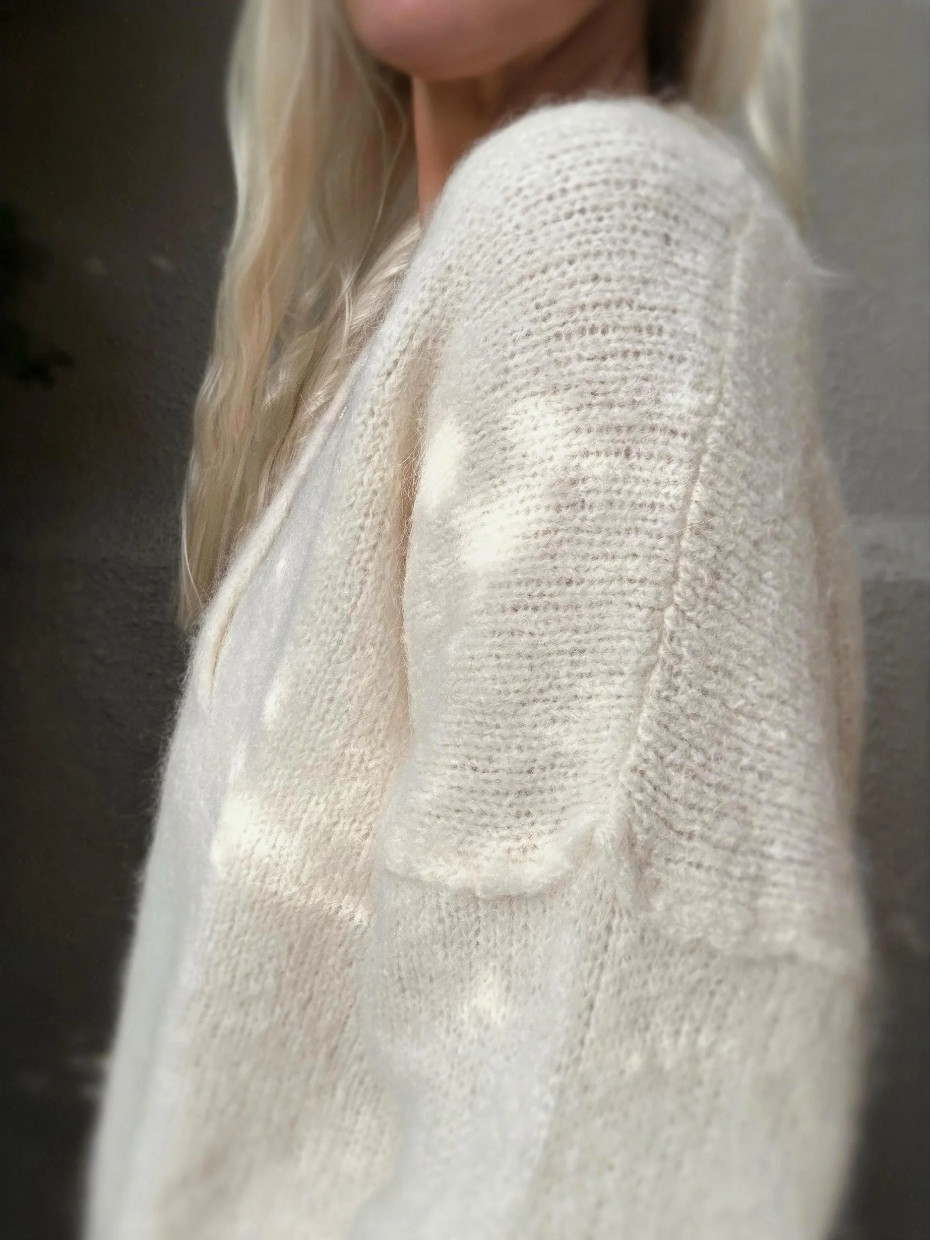 Side close-up of cream Banditas Kula V-Neck Sweater showing its textured knit, dropped shoulder and relaxed sleeve