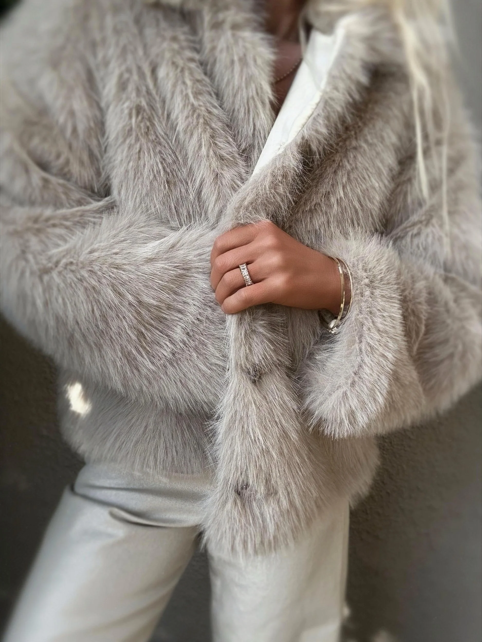 Woman wearing the cream Banditas Makena Faux Fur Jacket showing its open front and fluffy sleeves