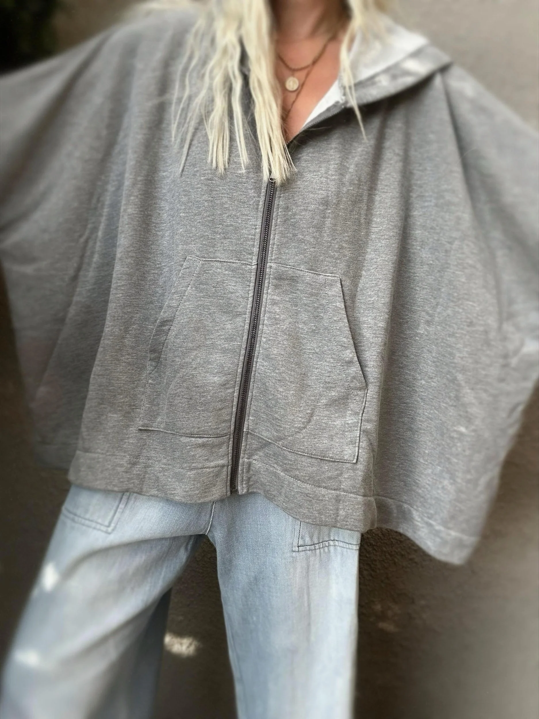 Woman wearing the grey Banditas Paradise sweatshirt unzipped over a white top