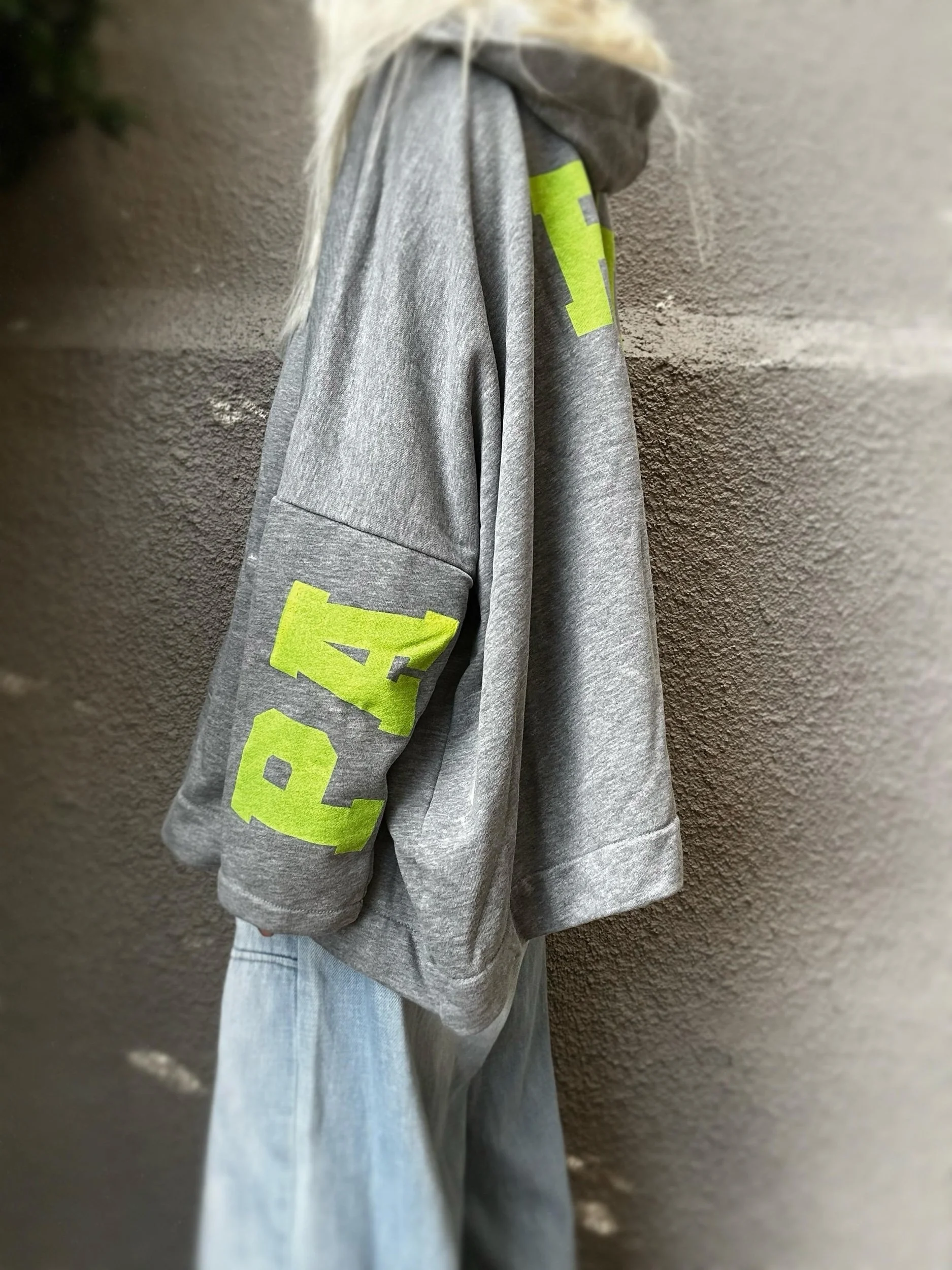 Side view of grey Banditas Paradise sweatshirt with neon green sleeve graphic