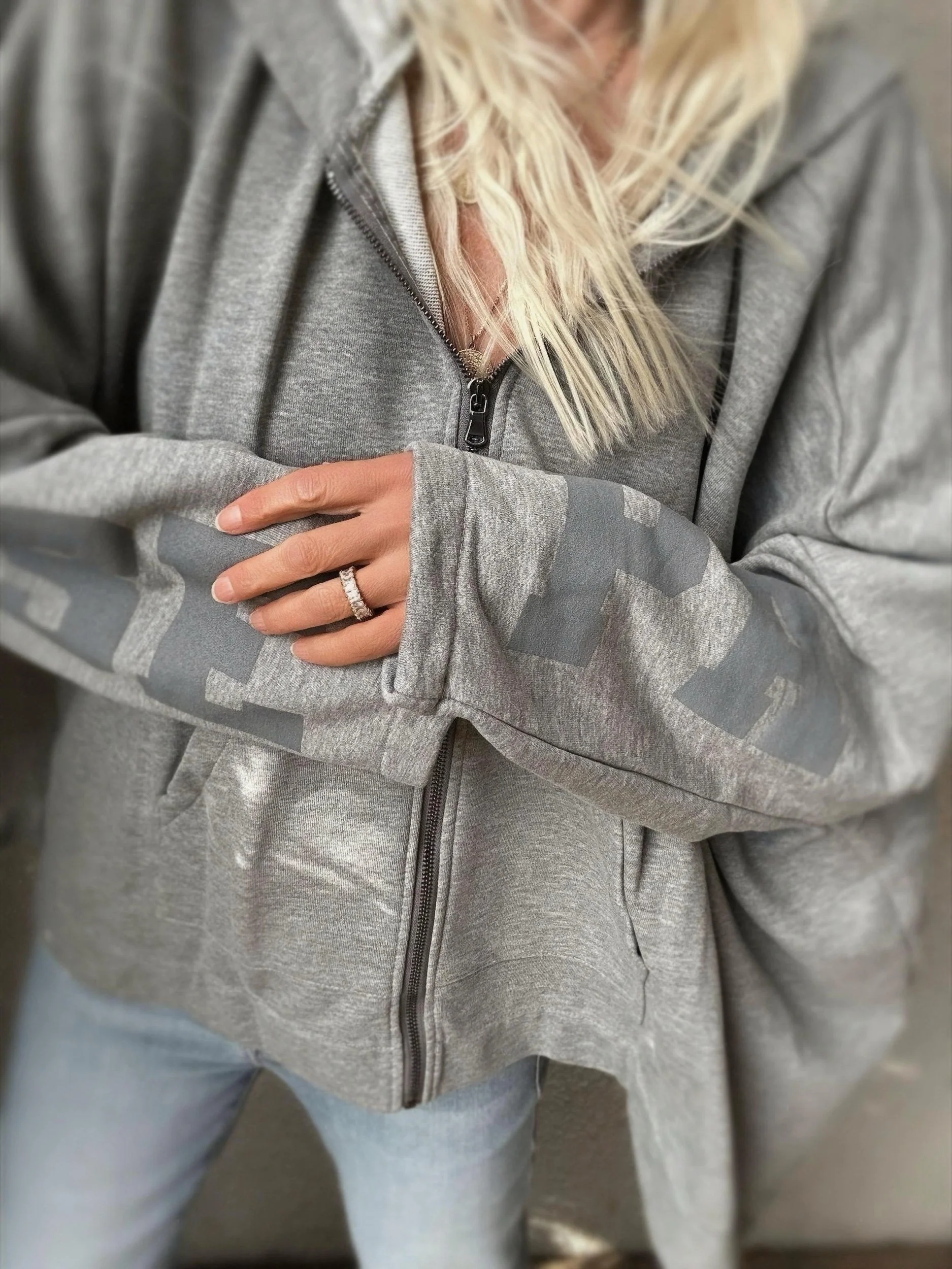 Woman wearing the oversized grey Banditas Paradise sweatshirt with zip front and relaxed sleeves