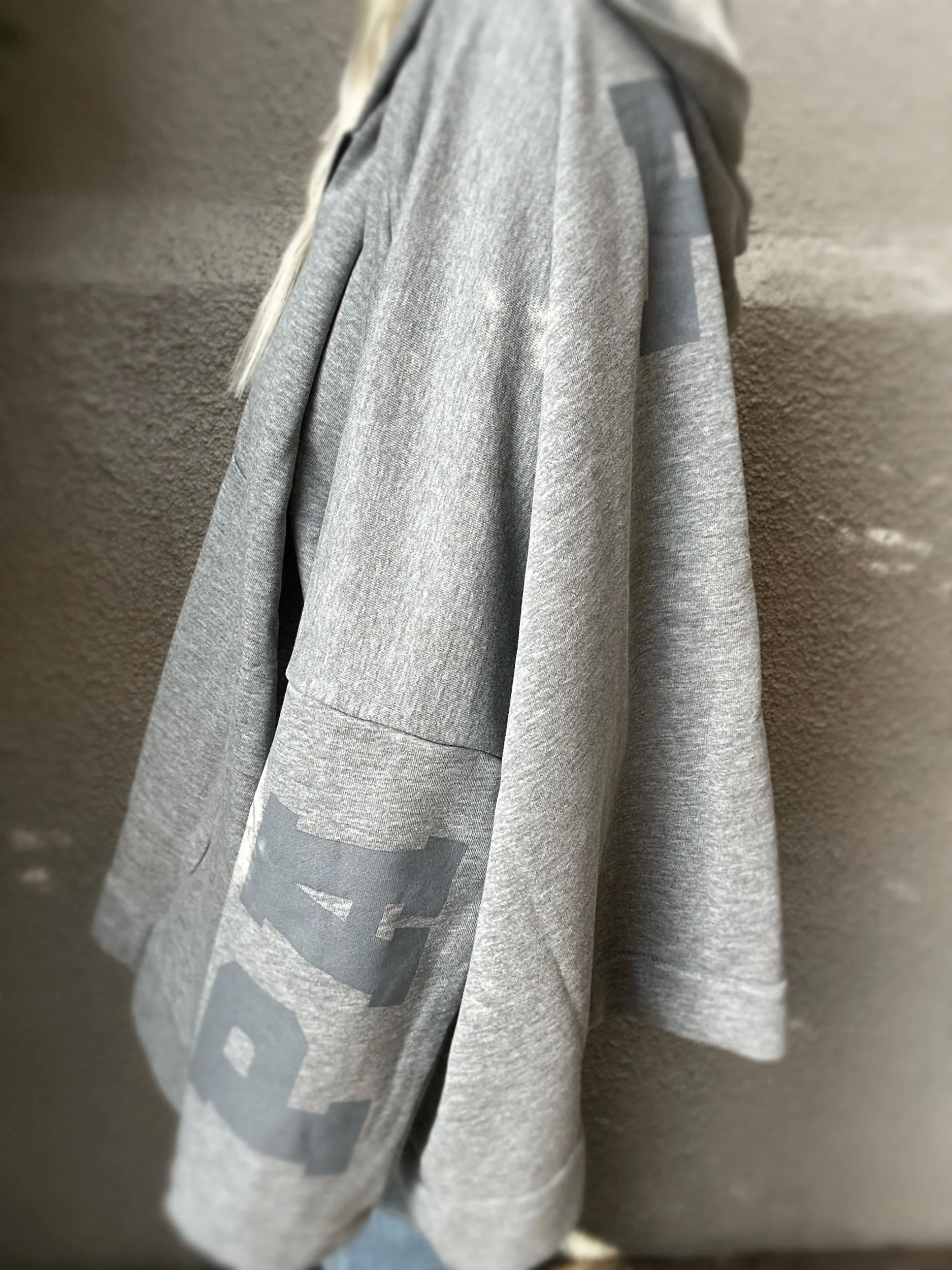 Side view of grey Banditas Paradise sweatshirt showing its loose, draped silhouette