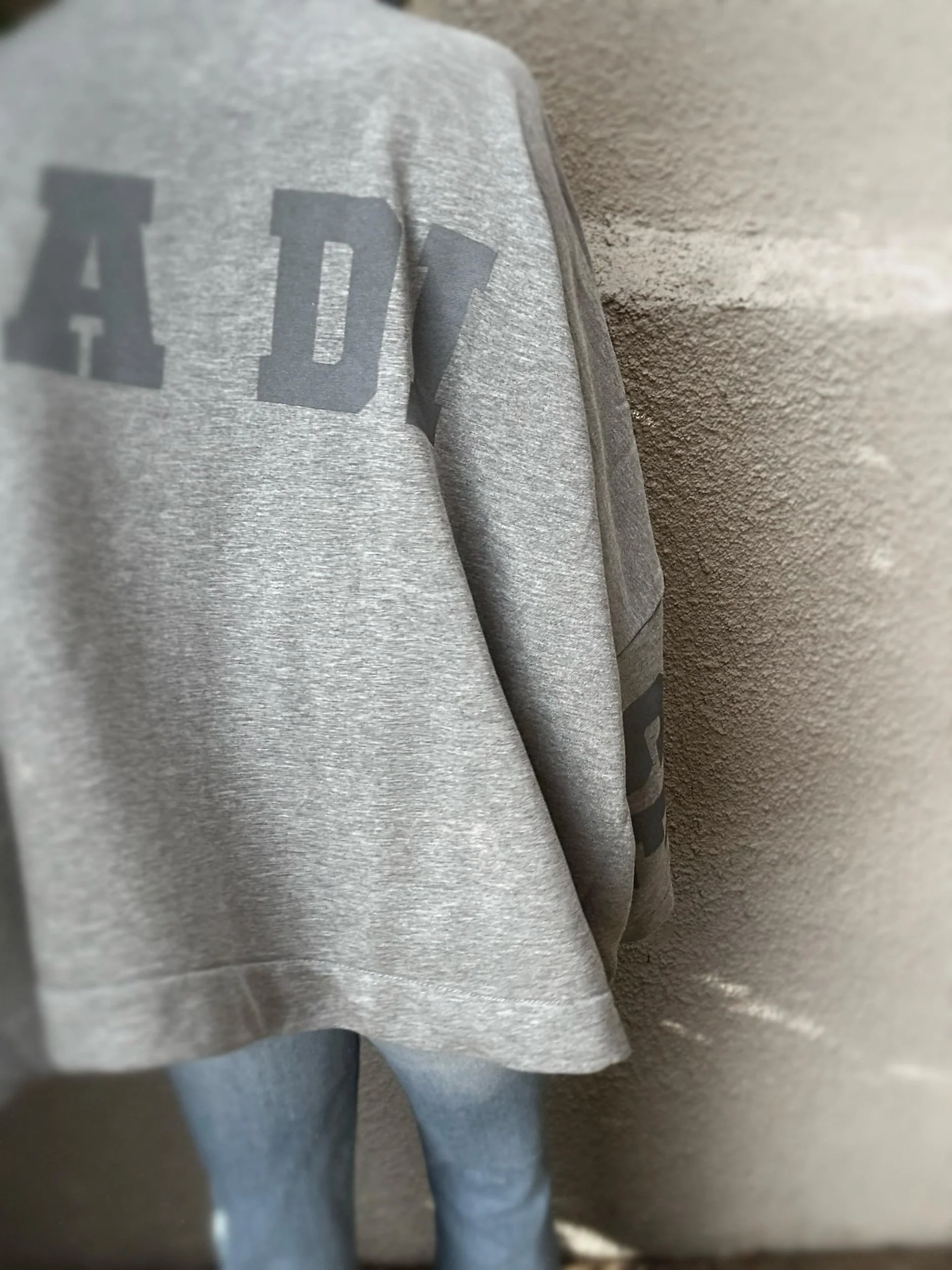 Close-up of grey Banditas Paradise sweatshirt showing dark grey lettering on the back