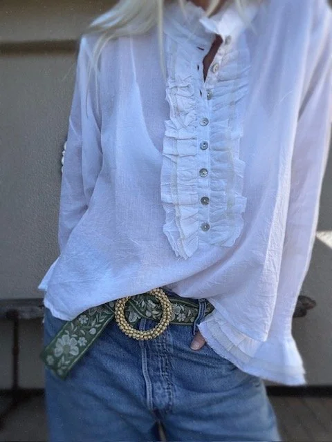 Detail of cream floral embroidery on the green belt.
