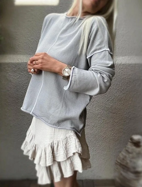Side detail of the Wren Long Sleeve Knit in grey highlighting the white-piped side slit, curved hem, and soft cotton drape.